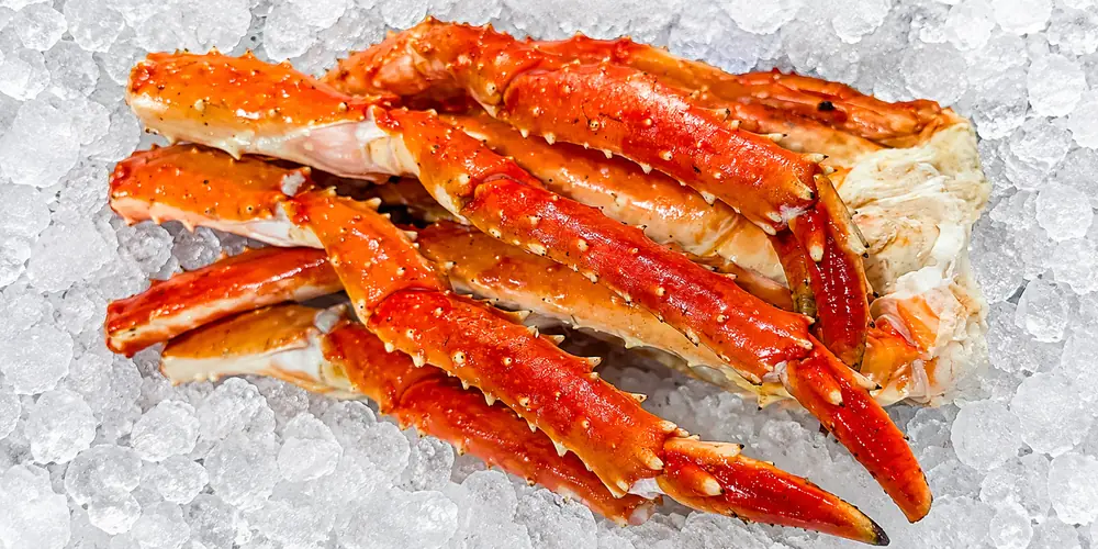 Orange-red king crab legs with white meat displayed on crushed ice
